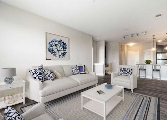 A living room with a white couch and a blue and white pillow.