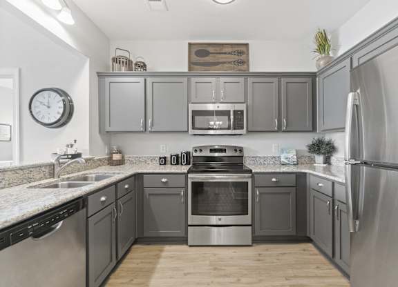 A kitchen with a stainless steel refrigerator and a stove with an oven.