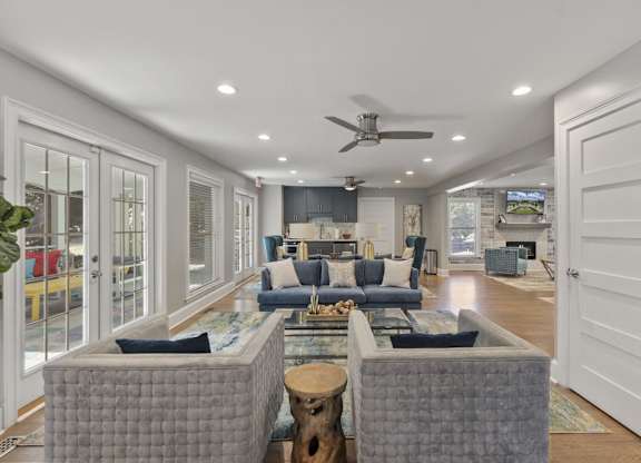 A clubhouse room with a grey sofa set and a ceiling fan.