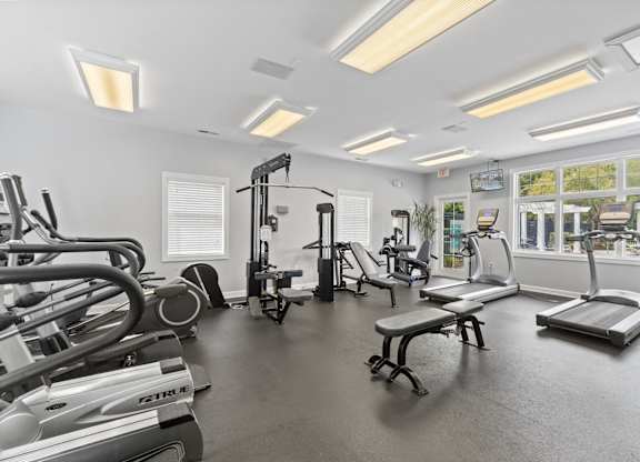 a gym with treadmills and other exercise equipment and windows