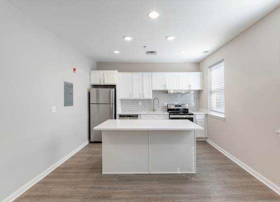 A kitchen with white cabinets and a wooden floor.