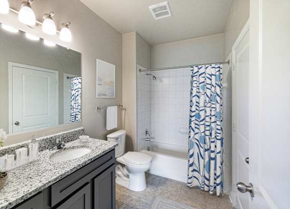 A bathroom with a white toilet, sink, and shower.