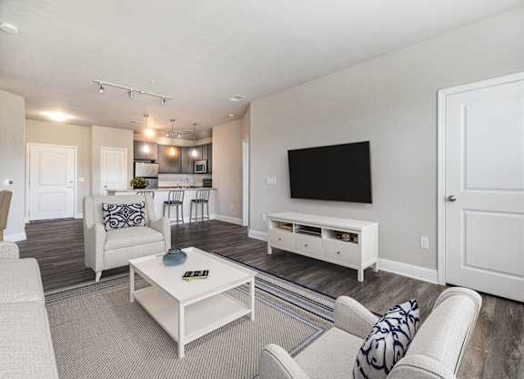 A living room with a white couch, a coffee table, and a television.