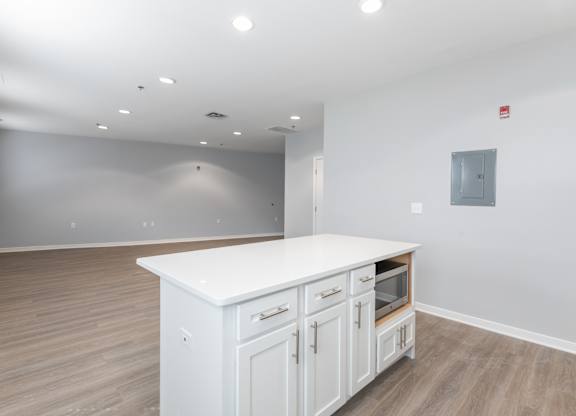 A white kitchen island with wooden cabinets in a room with a grey wall.