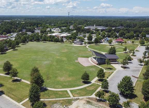 A large grassy field with a building and trees in the distance.