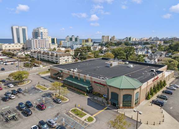 an aerial view of a building with a parking lot and a city in the background
