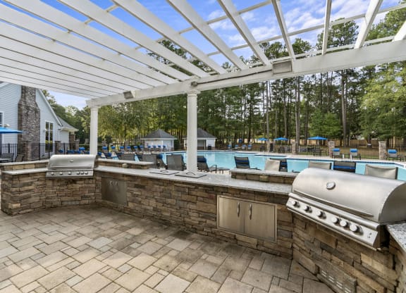 a covered outdoor kitchen with a pool in the background at Trails at Short Pump Apartments, Richmond, VA
