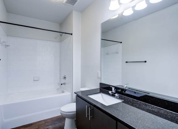 A white bathroom with black countertops and a black toilet.
