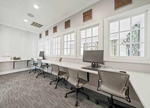 A room with a long desk and chairs with a computer on it.