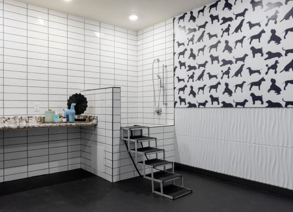 a bathroom with white tiles and a black and white pattern on the wall at Tapestry West, VA 23230