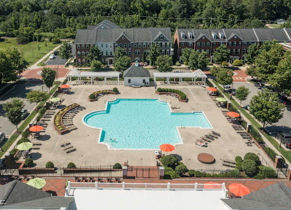 an aerial view of a swimming pool in front of a hotel with trees