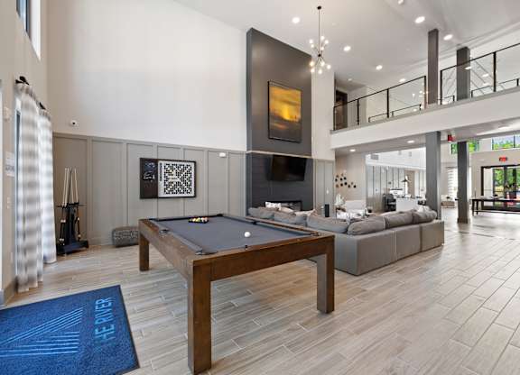 A pool table is in the middle of a room with a couch and a fireplace.
