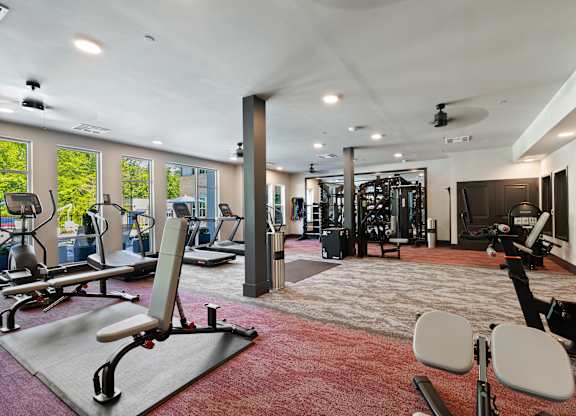 A gym with a variety of equipment including treadmills, weights, and exercise machines.