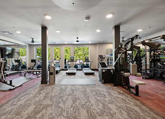 A gym with a variety of equipment and a large window.