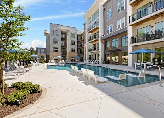 A pool area with a white fence and a blue umbrella.