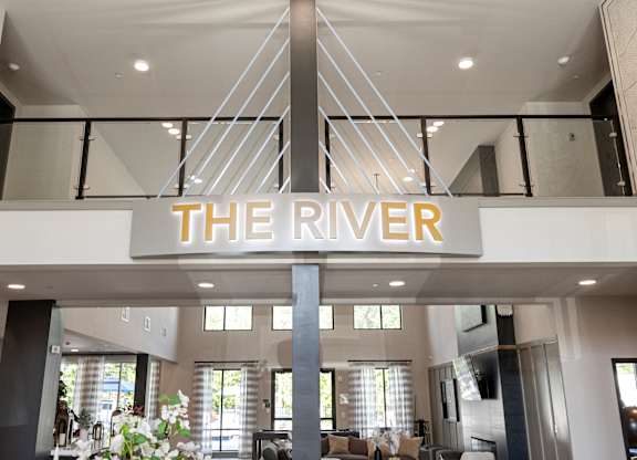 A sign that says "The River" hangs from a white ceiling.