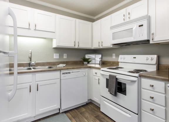 a kitchen with white appliances and white cabinets at Abbington Place Apartments, Greensboro