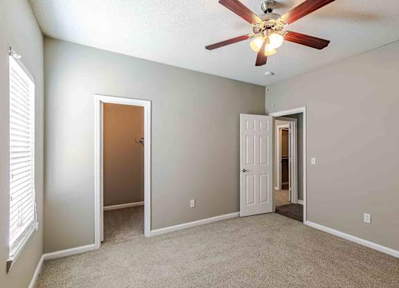 A room with a ceiling fan and two doors.