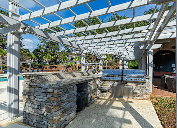 A patio with a stone fireplace and a pergola.