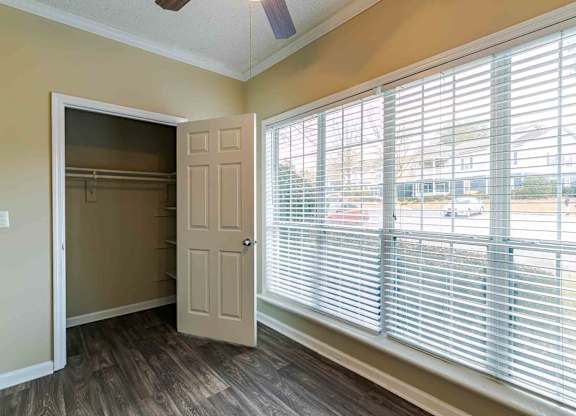 A room with a door open to a hallway and a window with blinds.