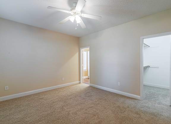 A room with a ceiling fan and carpeted floor.