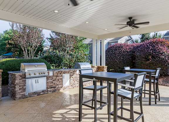 A patio with a table and chairs and a grill.