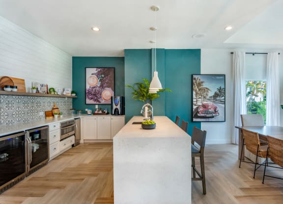 the kitchen and dining area of a house with blue walls and a large white island at The Villas at Ibis Landing, Parkland, FL