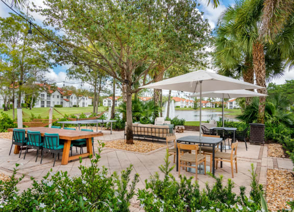 a patio with tables and chairs and trees at The Villas at Ibis Landing, Florida, 33067