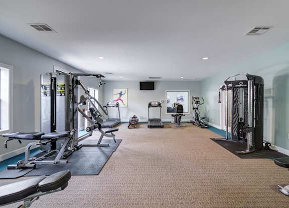A spacious gym with a variety of equipment including treadmills, weight machines, and benches.