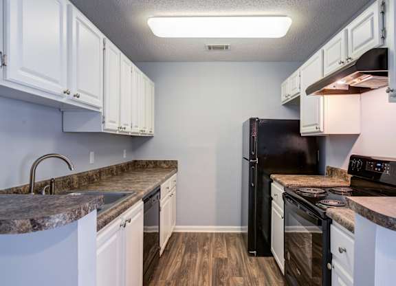A kitchen with black appliances and white cabinets.