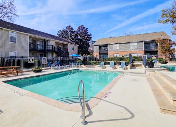A swimming pool surrounded by a concrete deck and a black fence.