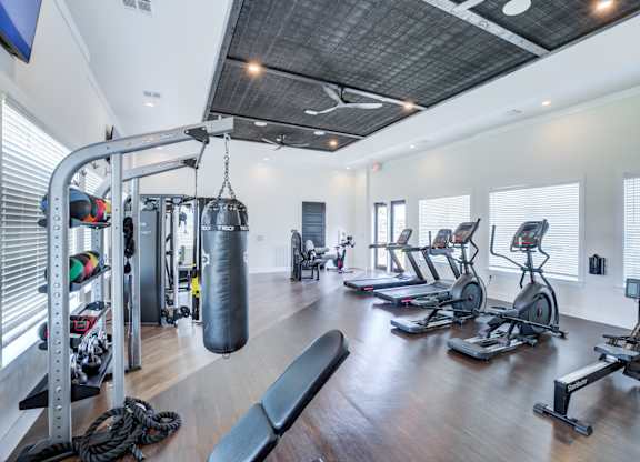 A gym with a variety of equipment including treadmills, weights, and a punching bag.