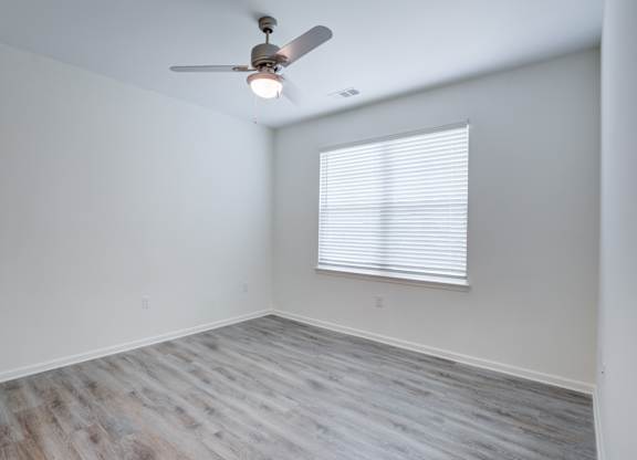 A room with a ceiling fan and a window with blinds.