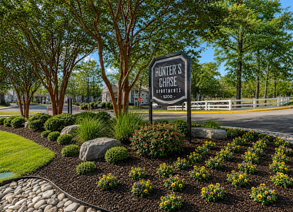 A sign for Hunter's Chase apartments stands in a landscaped area.