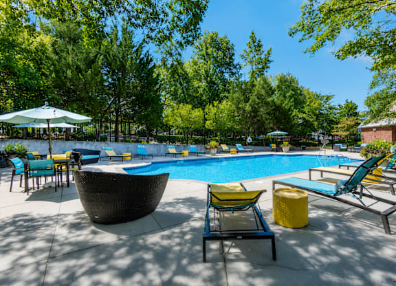 A pool area with a large round sculpture and lounge chairs.