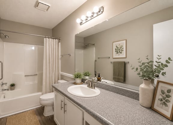 A bathroom with a sink, mirror, and shower.