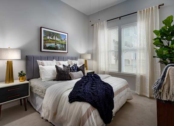 A bedroom with a bed, nightstand, and a painting on the wall.