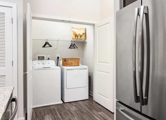 A kitchen with a refrigerator, washing machine, and dryer.