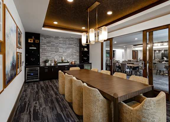 A modern kitchen with a long wooden table and chairs.