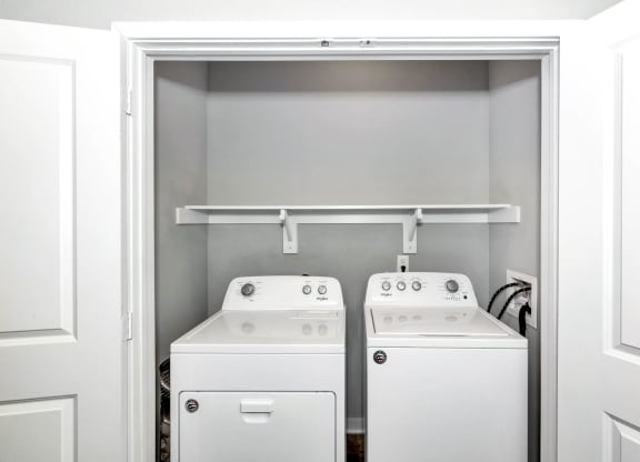 a white laundry room with two washes and a dryer at Farmhaus Apartments, Alabama