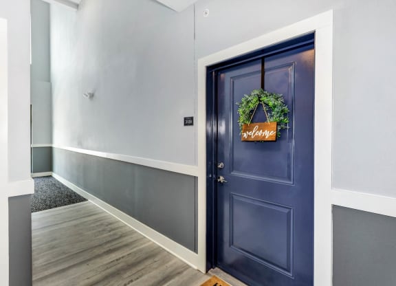 a hallway with a blue door with a wreath on it at Farmhaus Apartments, Madison, AL