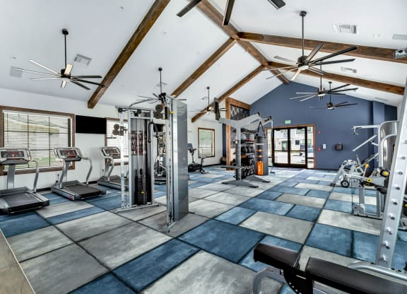 a gym with weights and cardio equipment and a ceiling with wooden beams at Farmhaus Apartments, Madison, AL, 35757