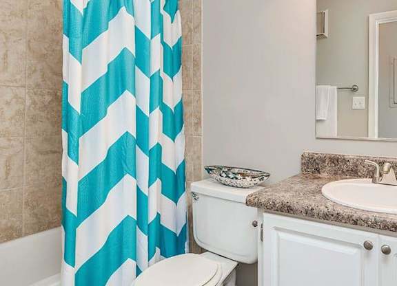 A bathroom with a white toilet, a sink, and a shower curtain. at Bradford Pointe, Georgia, 30909