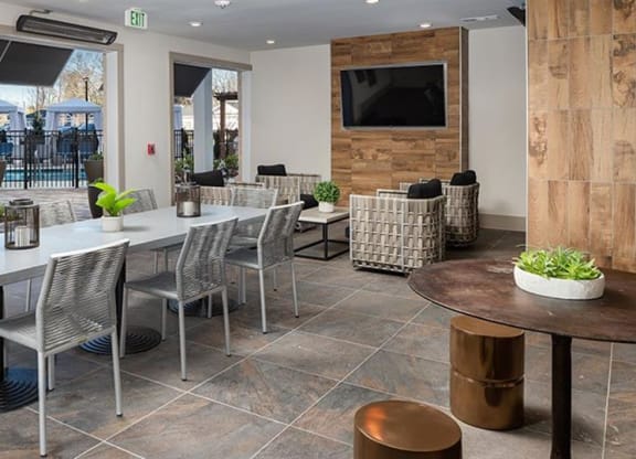 a dining room with tables and chairs and a television at The Flats at Southlawn Apartments, Lawrenceville, GA