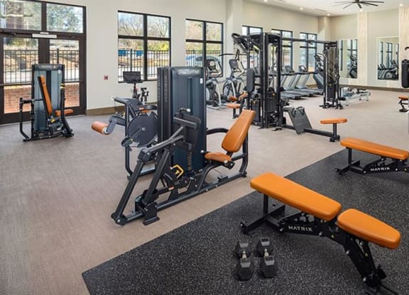 a gym with weights and other exercise equipment in a building at The Flats at Southlawn Apartments, Georgia