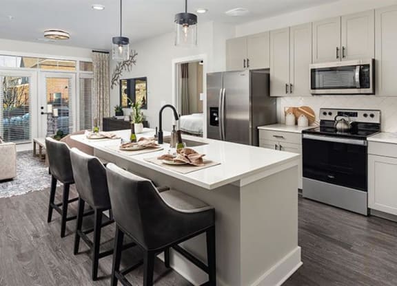 a kitchen with a large island with chairs at The Flats at Southlawn Apartments, Georgia, 30046