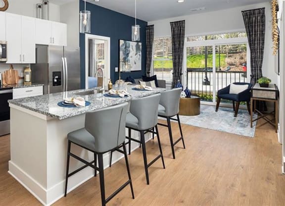 a kitchen with a large island with chairs at The Flats at Southlawn Apartments, Lawrenceville, 30046