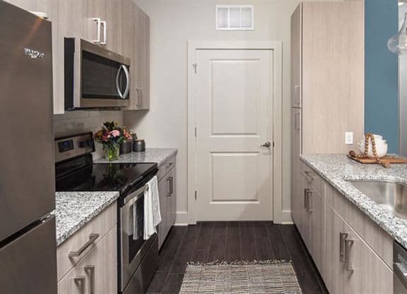 a kitchen with stainless steel appliances and marble counter tops at Promenade at Newnan Crossing, Newnan