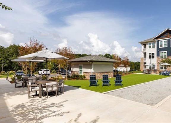 a patio with tables and chairs in front of an apartment building at Promenade at Newnan Crossing, Newnan Georgia