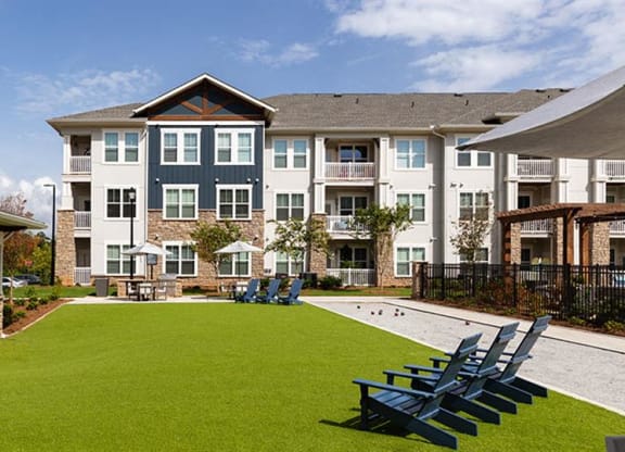 an outdoor lawn with chairs and a pool in front of an apartment building at Promenade at Newnan Crossing, Newnan, 30265